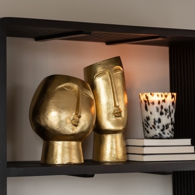 Prateleira preta com esculturas douradas e vela com manchas pretas