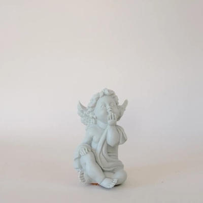 Estatueta de anjo branco sentado com asas em fundo branco