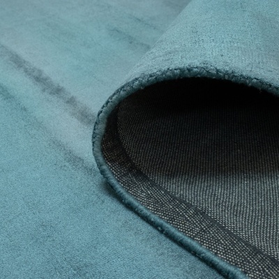 Tapete enrolado azul claro com verso em padrão de malha preta e cinza