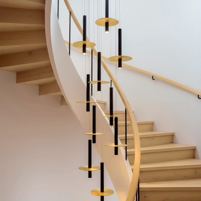 Escada caracol em madeira clara com iluminação pendente preta e dourada