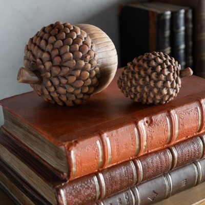 Ornamentos de madeira em forma de pinha em cima de livros antigos com capas de couro castanhas