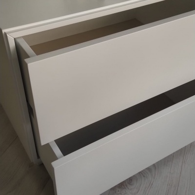 Cómoda branca com duas gavetas abertas e bulldog decorativo com coroa