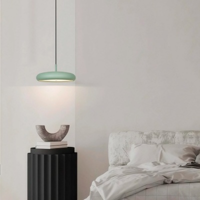 Quarto minimalista com cama estofada cinza claro, mesa de cabeceira preta ondulada e candeeiro verde claro pendente