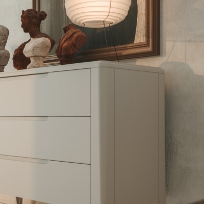 Móvel branco com lâmpada ovo e bustos decorativos sob quadro abstrato