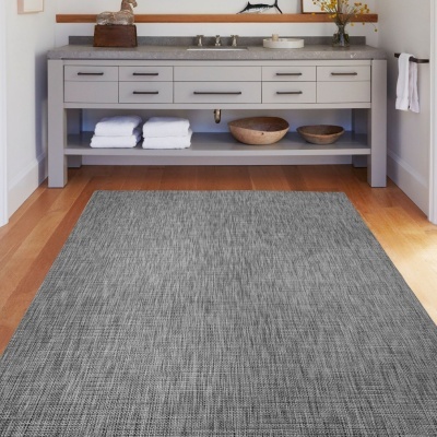 Tapete cinzento texturizado no chão de casa-de-banho com móvel cinzento e toalha branca