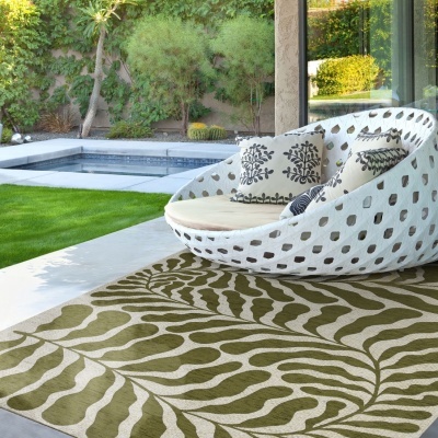 cadeira lounge branca com almofadas e tapete com padrão de folhas na varanda perto da piscina