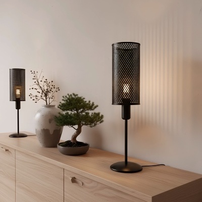 Candeeiros de mesa pretos com abajur perfurado em metal sobre móvel de madeira clara com vaso cerâmico e planta bonsai