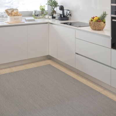 Tapete cinza na cozinha moderna com armários brancos e bancada com cesto de pão e frutas