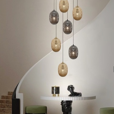 Candeeiros suspensos dourados e cinzentos, mesa branca com base escultural preta, bancos verdes e escadaria interior