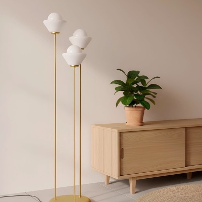 Luminária de pé dourada com globos brancos ao lado de móvel de madeira clara e planta em vaso de barro