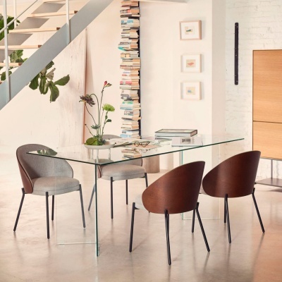 Mesa de jantar em vidro com quatro cadeiras cinza e marrons em ambiente moderno