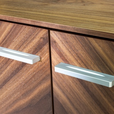 Peça de mobiliário de madeira castanha com puxadores metálicos prateados