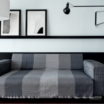 Sofá cinzento com padrão de riscas verticais em sala minimalista com luminária e quadros