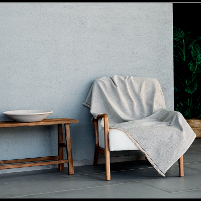 Cadeira de madeira com manta cinzenta e mesa de apoio com tigela branca