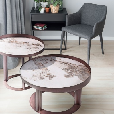 Mesa de centro redonda com tampo marmoreado e cadeira cinzenta num ambiente interior