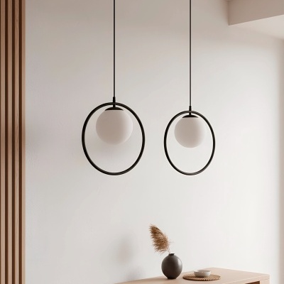 Lâmpadas pendentes modernas com globos brancos e estrutura circular preta sobre móvel de madeira clara com vaso cinza e prato branco.