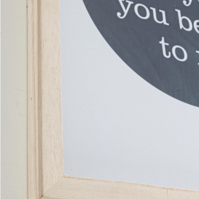 Pormenor de moldura de madeira clara com parte de um quadro com texto em branco sobre fundo preto