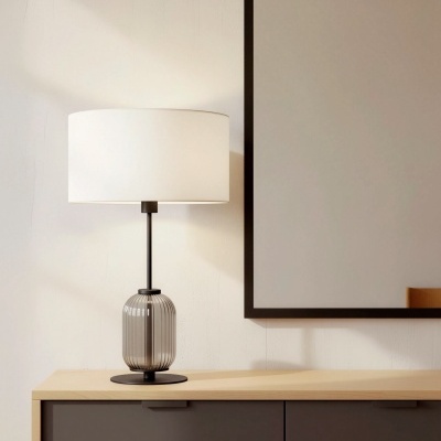 Candeeiro de mesa com base de vidro fumado e cúpula branca sobre móvel