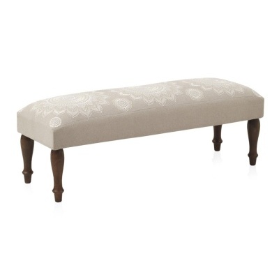 Banco almofadado bege com padrão floral branco e pernas de madeira escuras