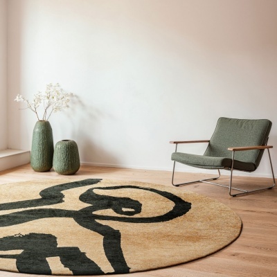 Tapete redondo bege com padrão preto, cadeira verde, dois vasos verdes com flores secas