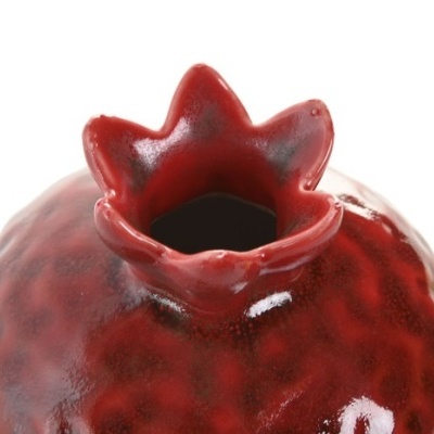 Fruto de romã de cerâmica vermelha brilhante com coroa distinta no topo.