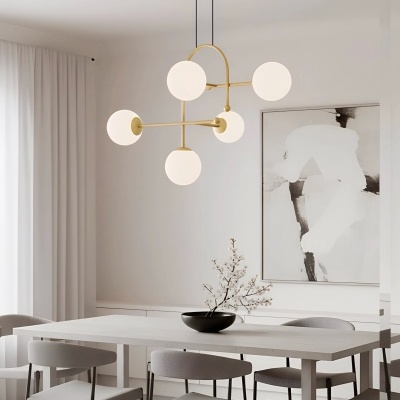 Sala de jantar minimalista com mesa branca, cadeiras cinza, candeeiro dourado com globos brancos, cortinas e quadro abstrato.