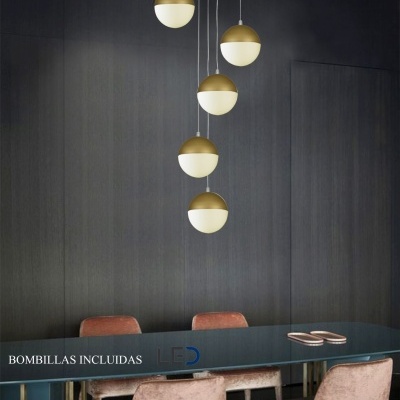 Lustre pendente com globos dourados e brancos sobre mesa de jantar azul e cadeiras cor de rosa