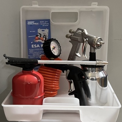 Kit de pintura com pistola prateada, recipiente vermelho, mangueira laranja e manómetro numa caixa branca