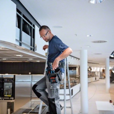 Homem em escada em espaço comercial moderno ajustando o teto