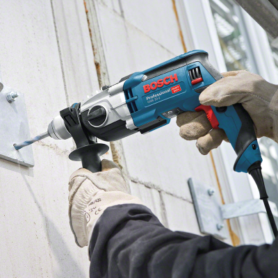 Furadeira Bosch Professional azul e preta a furar parede com luvas de proteção