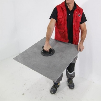 Homem com colete vermelho segura ventosa para azulejos cinza