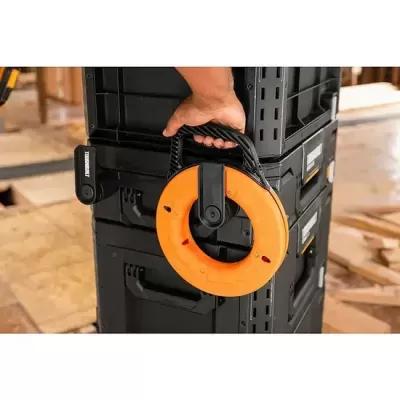 Bobina de fita métrica laranja com alça preta presa a caixa preta empilhada