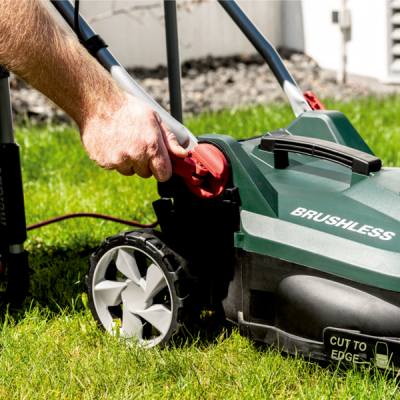 Corta-relvas eléctrico verde escuro com botão vermelho e texto BRUSHLESS