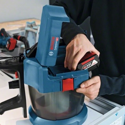 Aparadora de superfície Bosch azul com bateria preta e vermelha sendo instalada por uma pessoa
