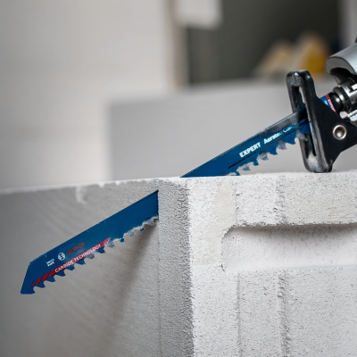 Serra azul com dentes metálicos a cortar bloco de cimento cinzento