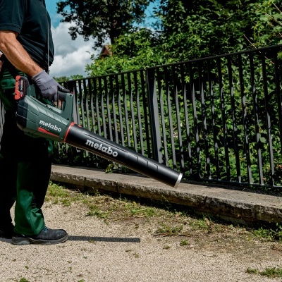 Soprador de folhas sem fio Metabo cinza escuro e preto em uso numa calçada