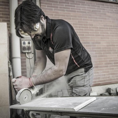 Homem a cortar pedra com rebarbadora em ambiente exterior