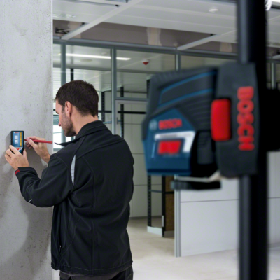 Homem a usar dispositivo de medição Bosch numa parede de concreto