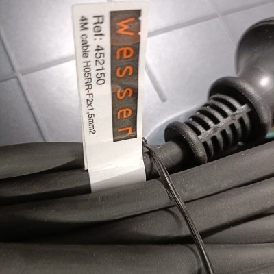 Cabo elétrico preto com etiqueta Wesser num fundo de azulejos claros