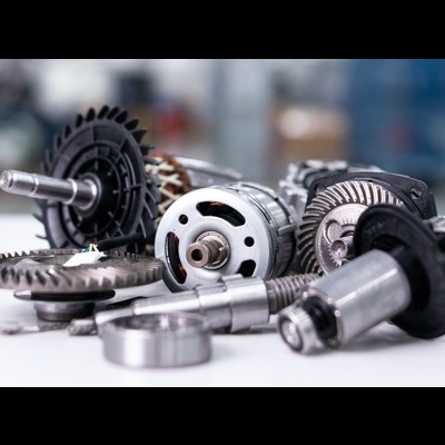 Peças industriais metálicas como engrenagens e motor elétrico numa bancada branca