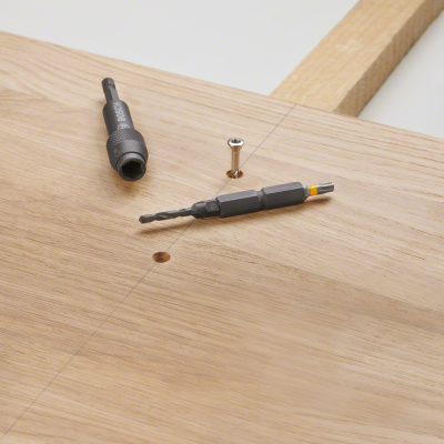 Brocas e parafuso sobre madeira clara com orifício perfurado