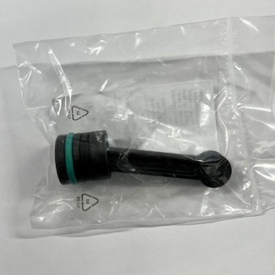 Peça plástica preta com anel verde embalada em saco plástico transparente