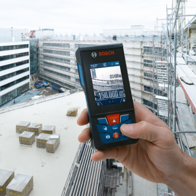 Aparelho medidor a laser BOSCH em mão num canteiro de obras