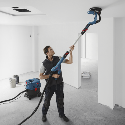 Homem usando lixadora eléctrica com aspiração em obra