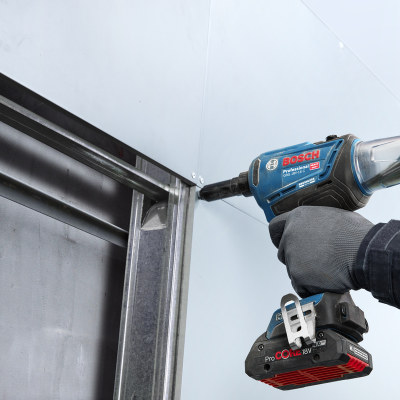 Parafusadeira elétrica azul Bosch em uso numa estrutura metálica.