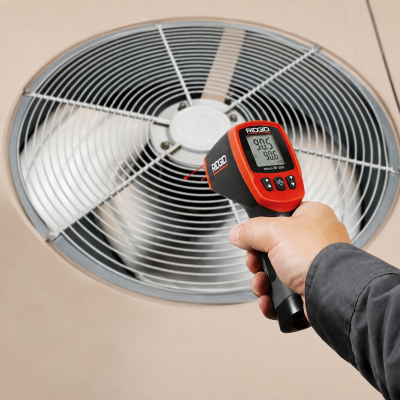 Termómetro infravermelho RIDGID preto e vermelho e ventilador metálico com grelha circular.