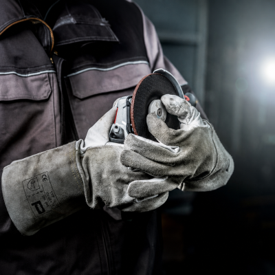 Luvas de trabalho cinzentas de pele com esmerilhadeira e disco abrasivo.