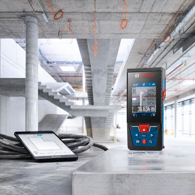 Aparelho de medição laser Bosch e tablet mostrando desenho técnico numa obra em betão