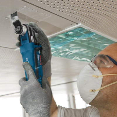 Ferramenta elétrica BOSCH Professional a ser usada por pessoa com luvas e máscara no teto
