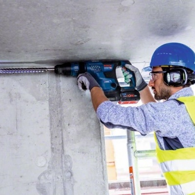 Homem a usar pistola elétrica numa superfície de tecto em obra